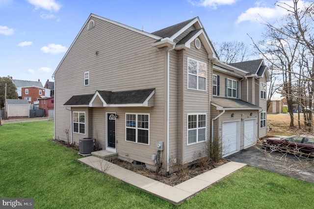 exterior space with cooling unit, a front lawn, a garage, and driveway