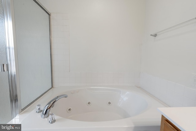 full bathroom featuring a jetted tub and vanity