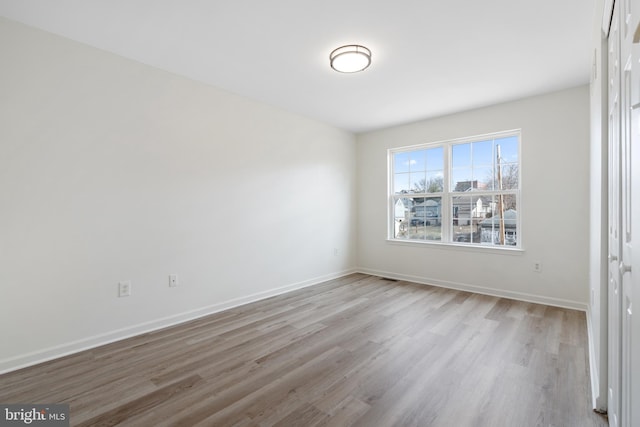 spare room featuring baseboards and wood finished floors