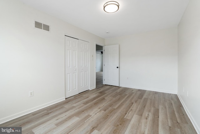 unfurnished bedroom with a closet, visible vents, baseboards, and wood finished floors