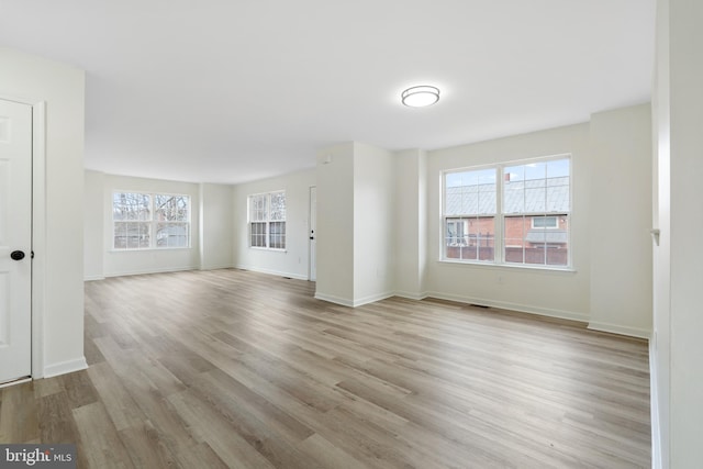 unfurnished living room with baseboards and light wood finished floors