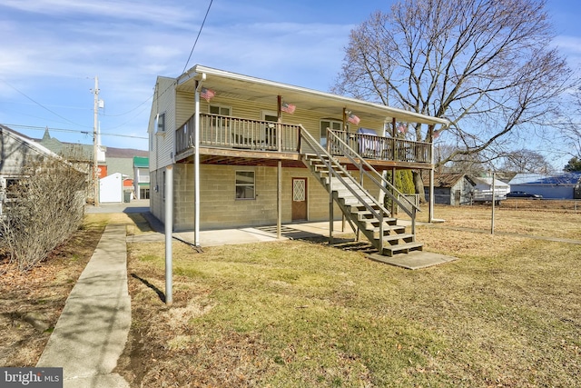 rear view of property with stairway, a lawn, a wooden deck, and a patio