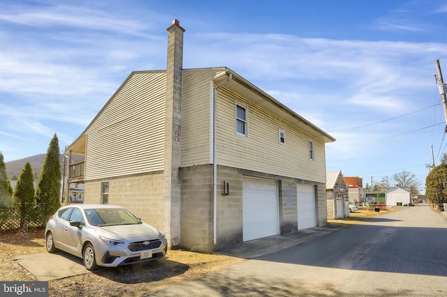 view of side of property featuring an attached garage and a chimney