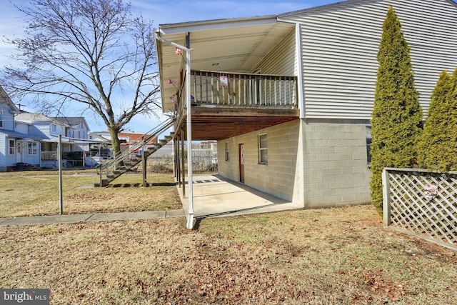 view of side of property featuring a patio area, stairway, and a lawn