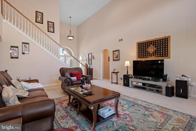 living room featuring stairway, carpet, visible vents, a high ceiling, and arched walkways