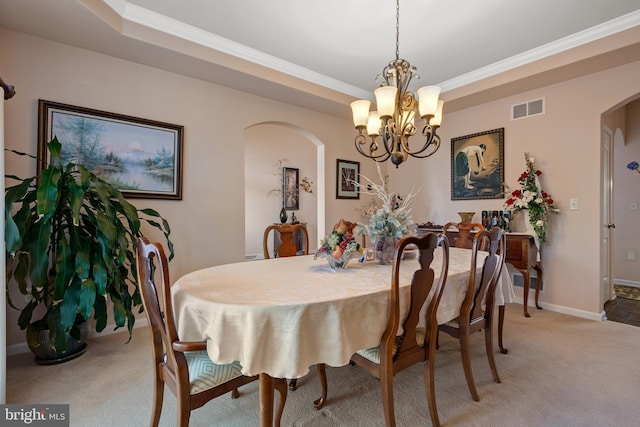 dining room featuring visible vents, arched walkways, a raised ceiling, and light carpet