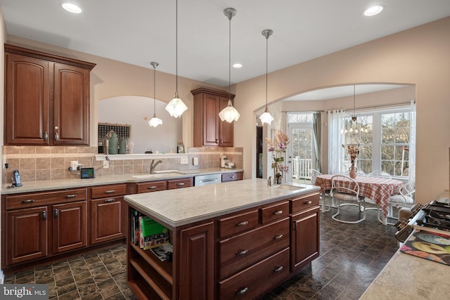 kitchen with decorative light fixtures, arched walkways, backsplash, and a sink