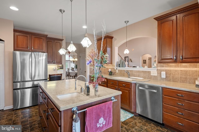 kitchen with arched walkways, tasteful backsplash, appliances with stainless steel finishes, and a sink