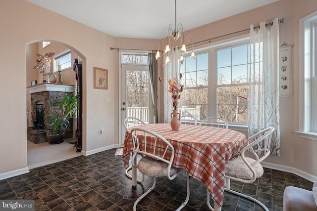 dining room with arched walkways, plenty of natural light, a chandelier, and baseboards