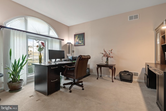 office area with baseboards, visible vents, and light carpet