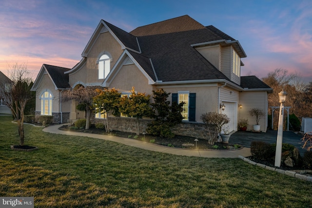 view of front of property with roof with shingles, a yard, stucco siding, a garage, and stone siding