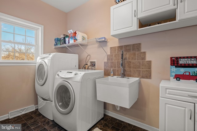 clothes washing area featuring visible vents, washer and clothes dryer, a sink, cabinet space, and baseboards