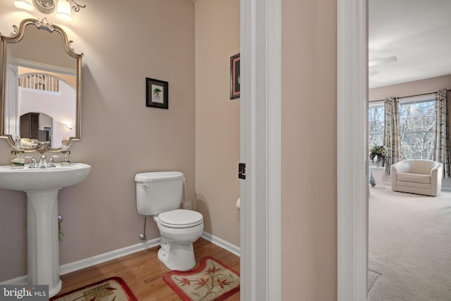 bathroom featuring toilet, wood finished floors, and baseboards