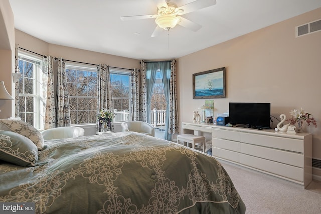 carpeted bedroom featuring visible vents, multiple windows, and ceiling fan