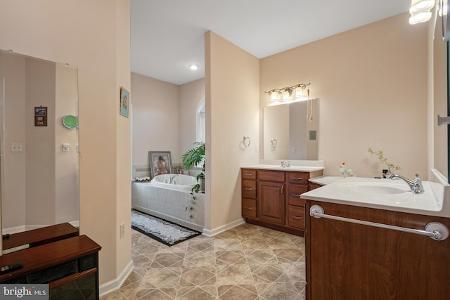 bathroom featuring a bath, two vanities, baseboards, and a sink