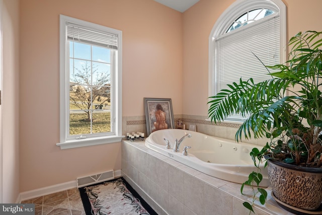 bathroom featuring tile patterned floors, visible vents, plenty of natural light, and a whirlpool tub