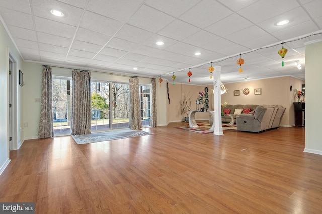 unfurnished living room featuring recessed lighting, wood finished floors, baseboards, and a drop ceiling