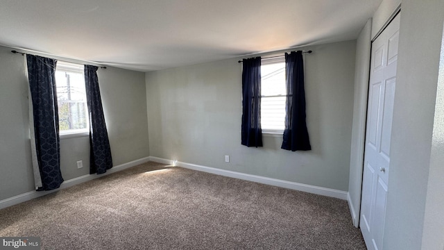 unfurnished bedroom with a closet, multiple windows, baseboards, and carpet