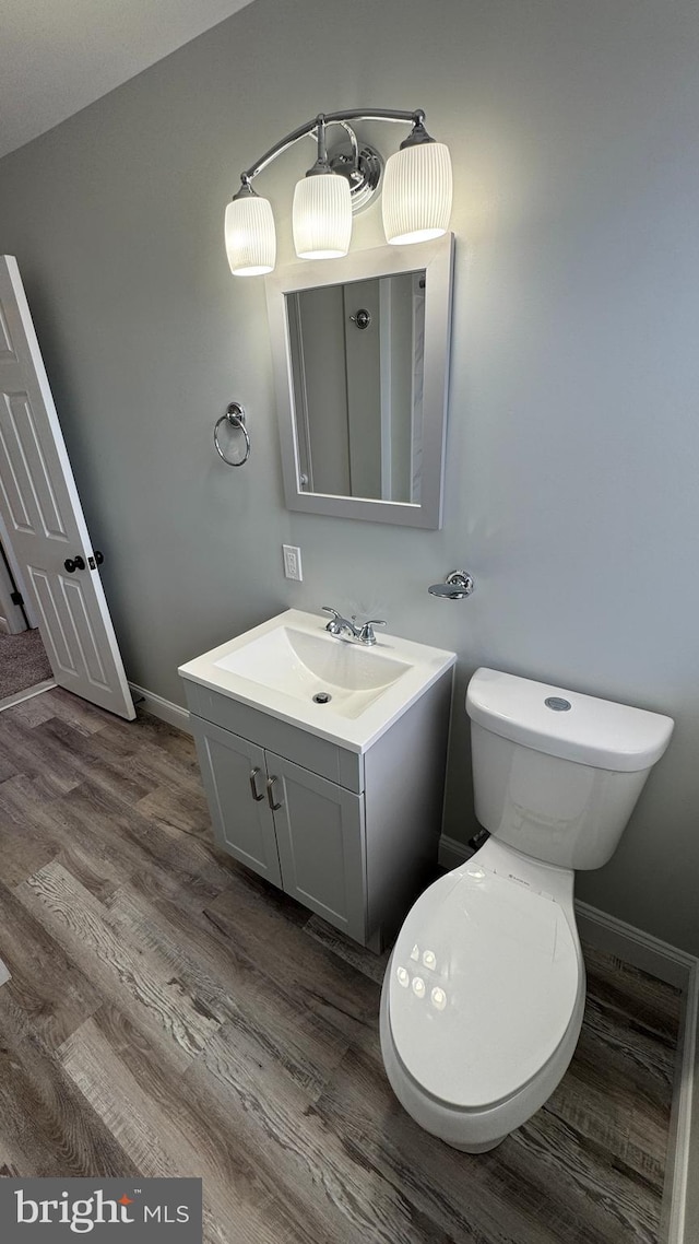 bathroom with baseboards, toilet, wood finished floors, and vanity