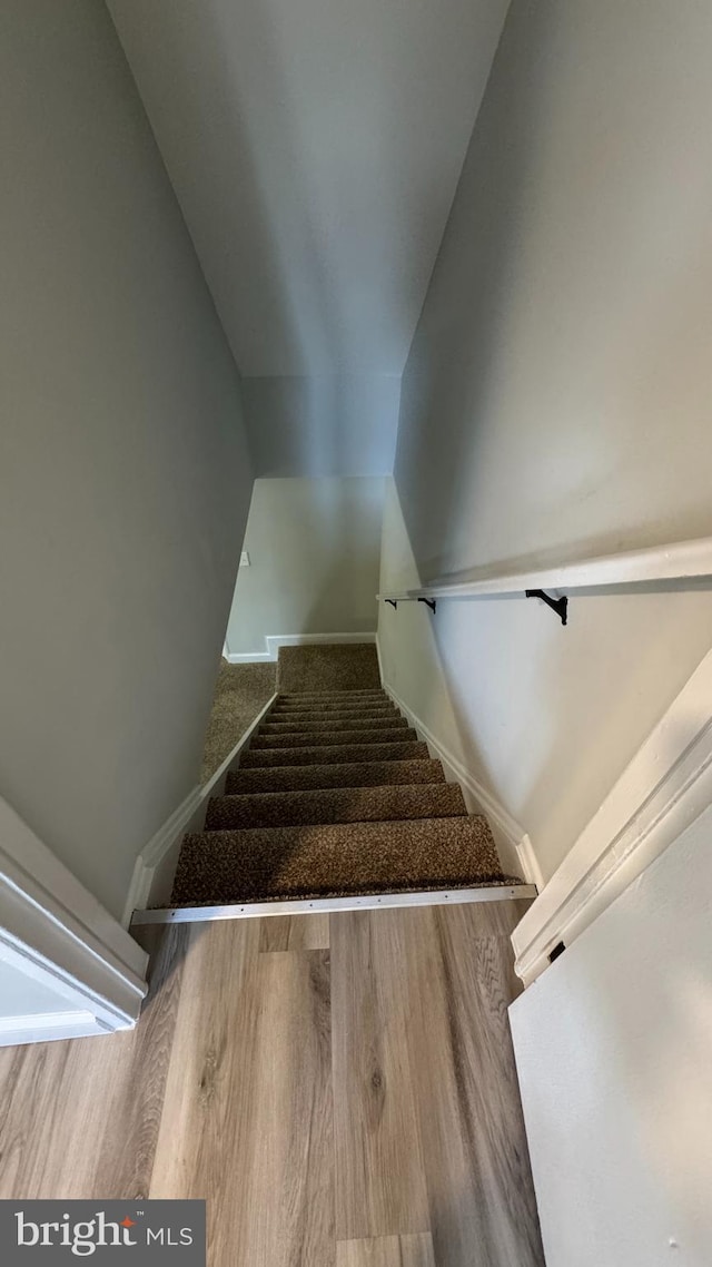 stairway with baseboards, lofted ceiling, and wood finished floors