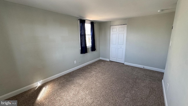 unfurnished bedroom featuring a closet, baseboards, and dark carpet