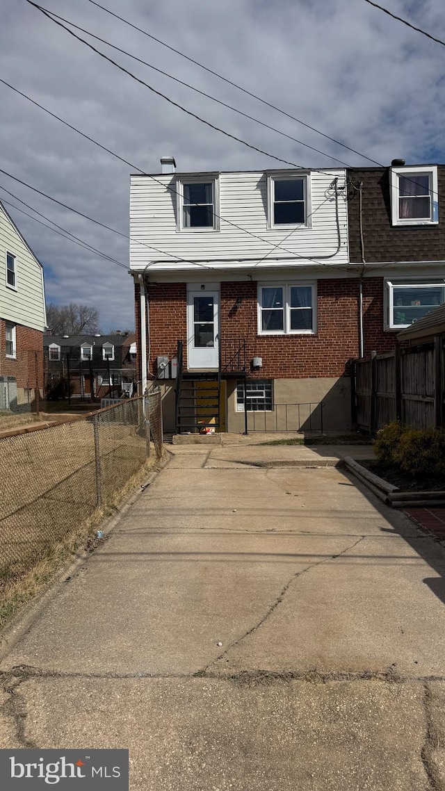 view of side of home with fence, brick siding, and entry steps