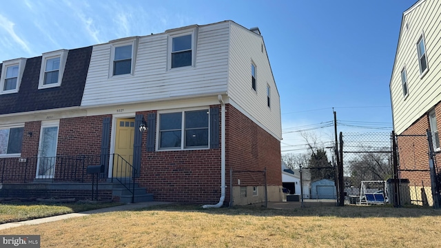 view of front facade with brick siding, a front lawn, and fence