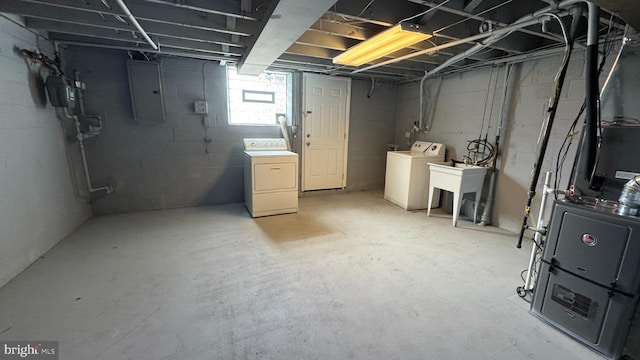 basement featuring electric panel, washer and dryer, and a sink