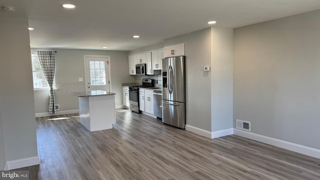 kitchen featuring visible vents, a kitchen island, white cabinets, stainless steel appliances, and dark wood-style flooring