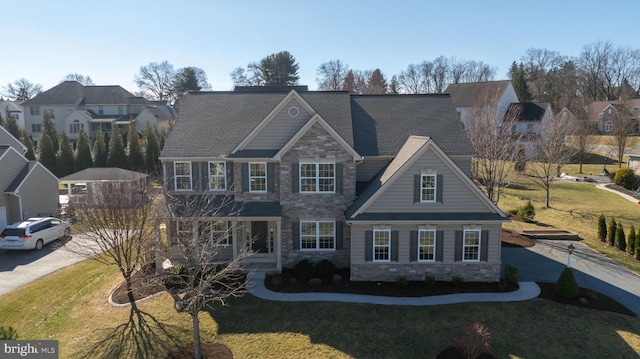 view of front facade with stone siding, driveway, and a front lawn