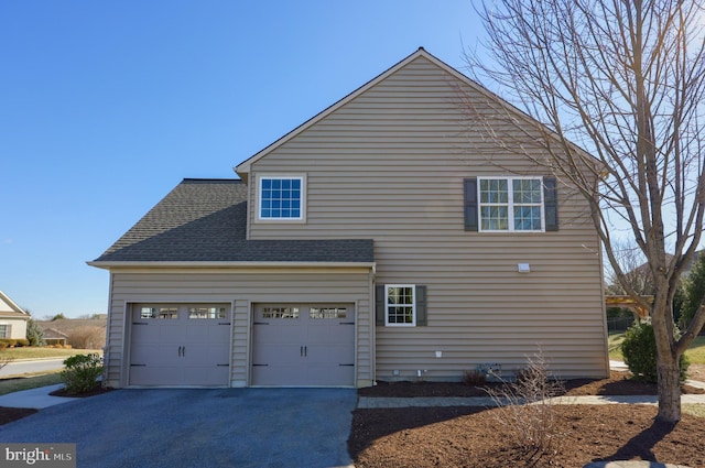 view of property exterior with aphalt driveway, an attached garage, and roof with shingles