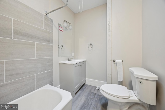 bathroom with toilet, a bathtub, wood finished floors, vanity, and a shower