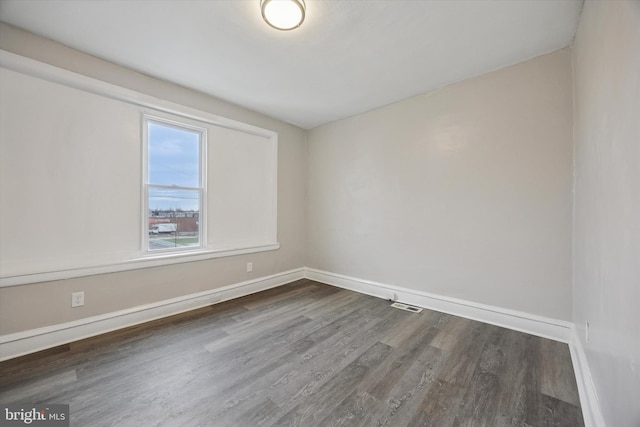 spare room featuring visible vents, baseboards, and dark wood finished floors