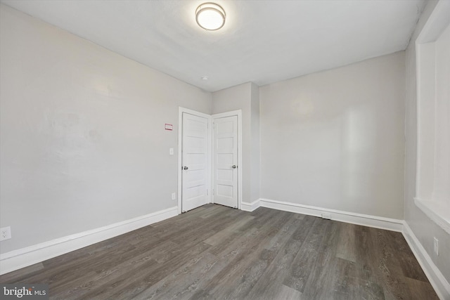 unfurnished room with dark wood finished floors and baseboards