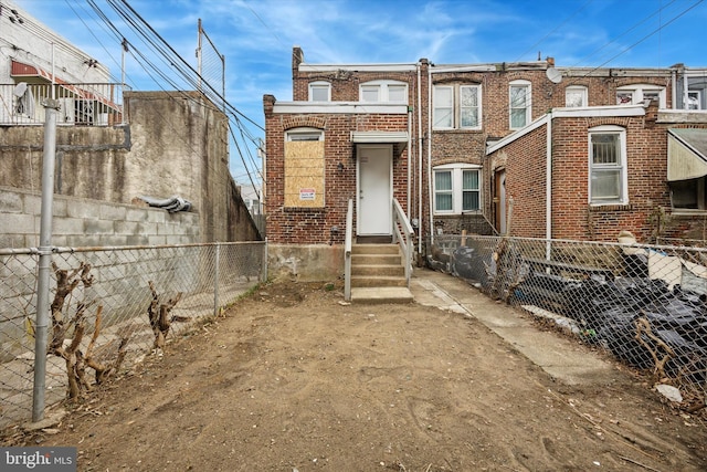 view of front of property with brick siding, entry steps, and fence