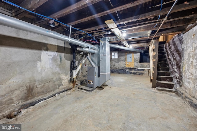 basement with electric panel, stairway, and heating unit