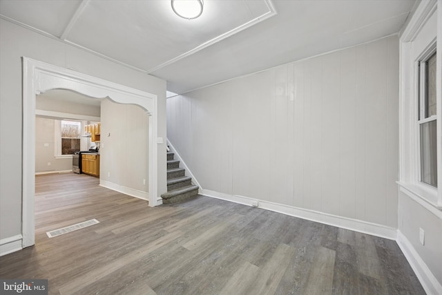 spare room featuring visible vents, baseboards, wood finished floors, and stairs