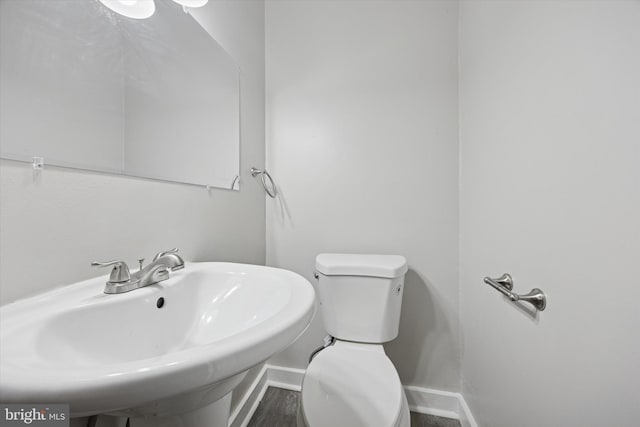 bathroom featuring toilet, baseboards, and a sink