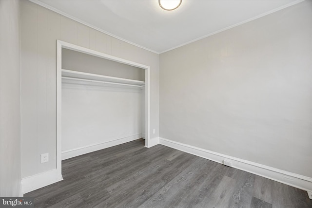 unfurnished bedroom with a closet, baseboards, ornamental molding, and dark wood finished floors