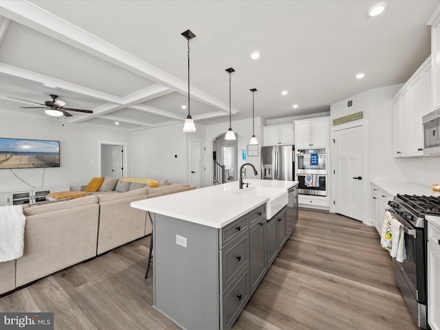 kitchen featuring recessed lighting, gray cabinets, wood finished floors, stainless steel appliances, and a sink