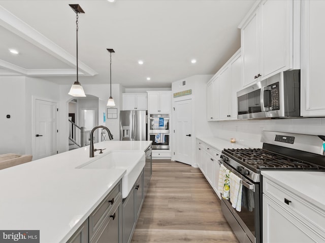 kitchen with gray cabinets, a sink, stainless steel appliances, light countertops, and light wood-type flooring