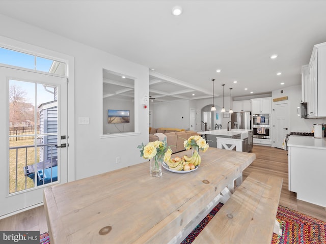 dining area with a ceiling fan, recessed lighting, light wood-style floors, and arched walkways