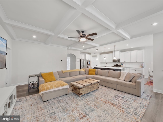 living area with baseboards, arched walkways, and wood finished floors