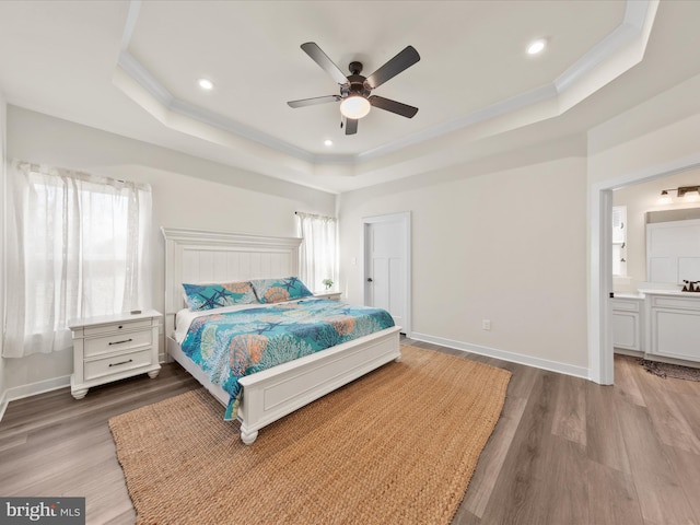 bedroom featuring baseboards, a raised ceiling, and wood finished floors