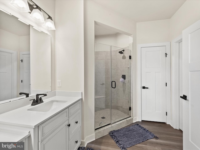 full bath featuring a stall shower, vanity, and wood finished floors