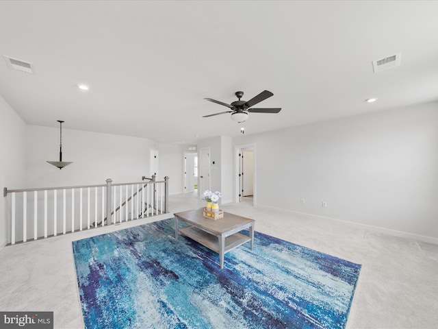 living area featuring carpet, an upstairs landing, visible vents, and baseboards