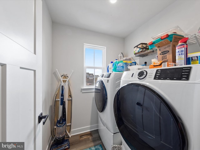 washroom featuring visible vents, baseboards, washer and clothes dryer, laundry area, and wood finished floors