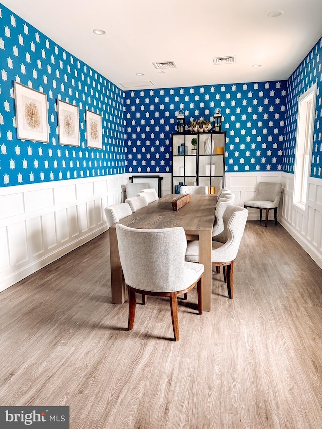 dining room featuring visible vents, wallpapered walls, and wood finished floors