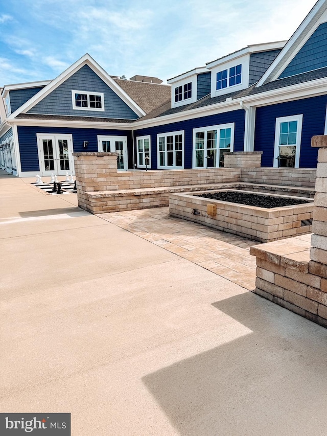 exterior space with a patio area, french doors, and a shingled roof