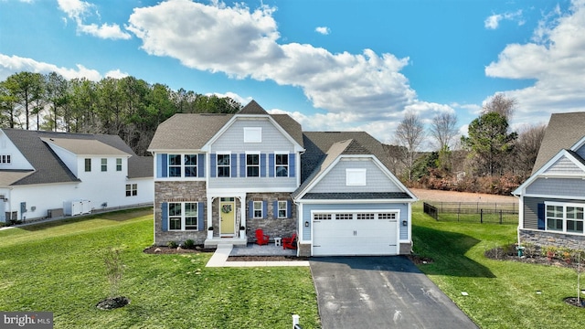 view of front facade with stone siding, a front lawn, driveway, and fence